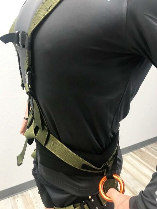 Close-up of a safety body harness with adjustable black and green straps for secure fit.