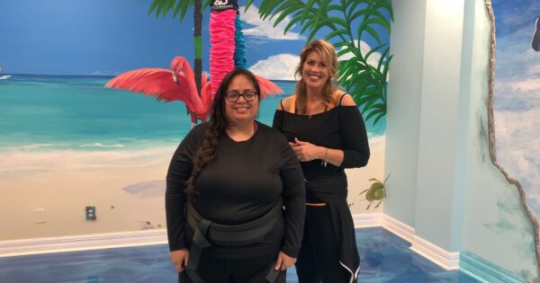 Friends enjoying tropical vibes in a colorful beach-themed room with a vibrant mural.