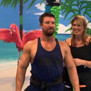 Joyful couple in tropical setting, showcasing fitness and fun with vibrant beach backdrop.