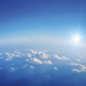 Stunning aerial view of Earth showcasing clouds, ocean, and a radiant sun on the horizon.