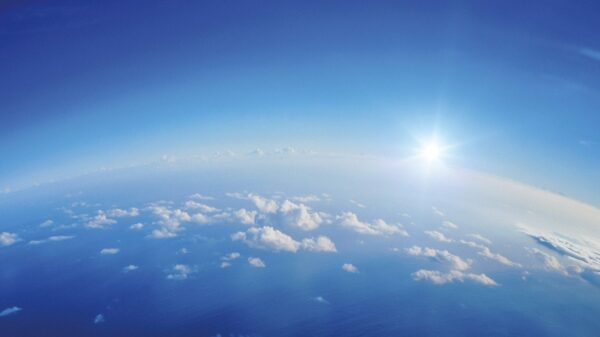 Stunning aerial view of Earth showcasing clouds, ocean, and a radiant sun on the horizon.