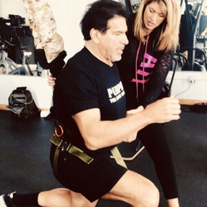 Personal trainer assisting a man in a fitness workout at the gym.