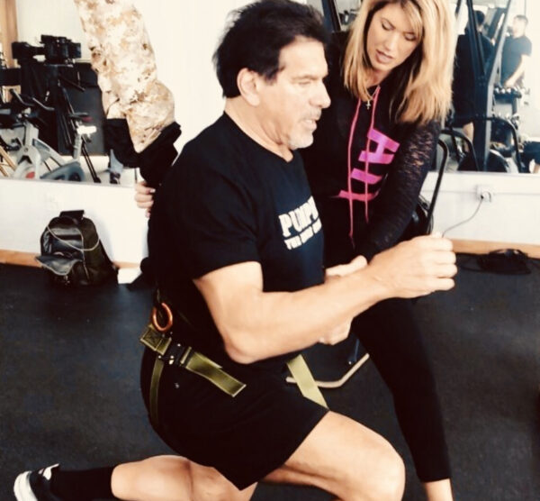 Personal trainer assisting a man in a fitness workout at the gym.